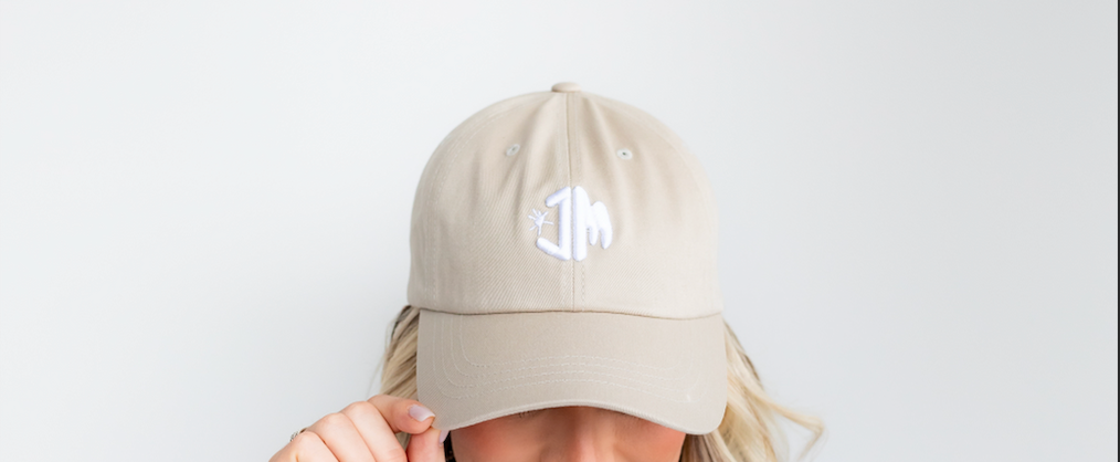 Female model wearing beige JM logo hat